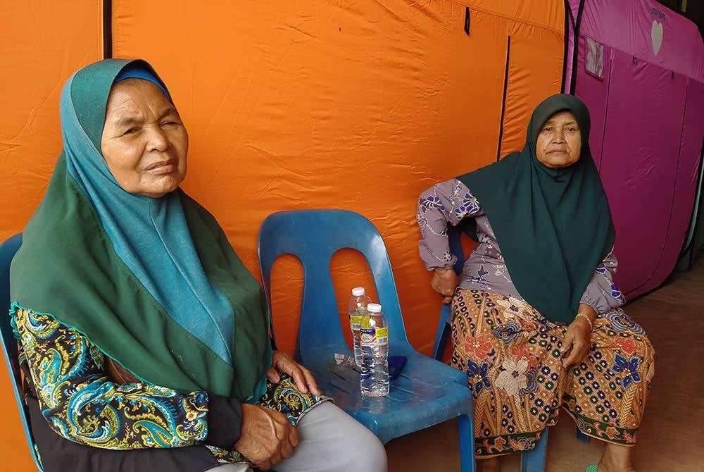 Siti Mariam (kanan) dan Che Mah ketika ditemui di PPS Dewan Kampung Padang Empang Kupang Baling pada Rabu.