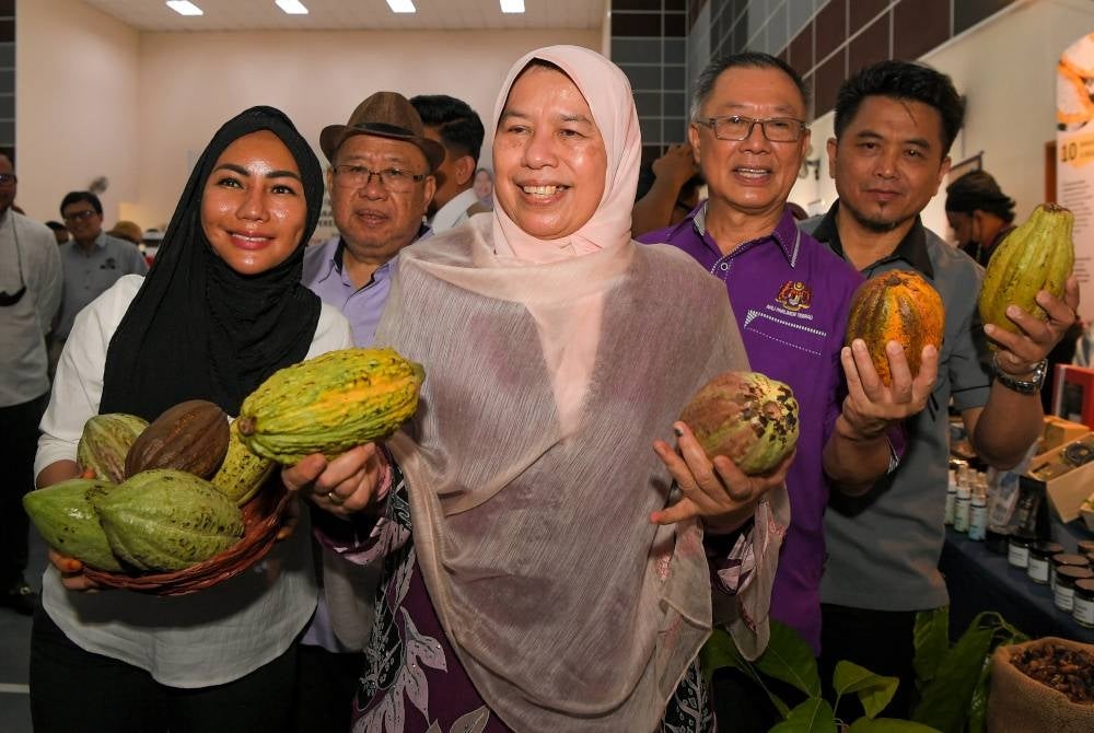 Menteri Perusahaan Perladangan dan Komoditi Datuk Zuraida Kamaruddin (tengah) menunjukkan koko yang terdapat di gerai pameran pada Majlis Program Jelajah Agrikomoditi Keluarga Malaysia di Dewan Semai Bakti Felda Inas Utara, pada Jumaat. - Foto Bernama