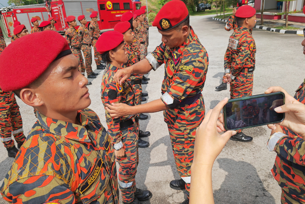 Nor Hisham memakaikan lencana kepada anggota bomba yang berjaya menamatkan kurusus asas hazmat.