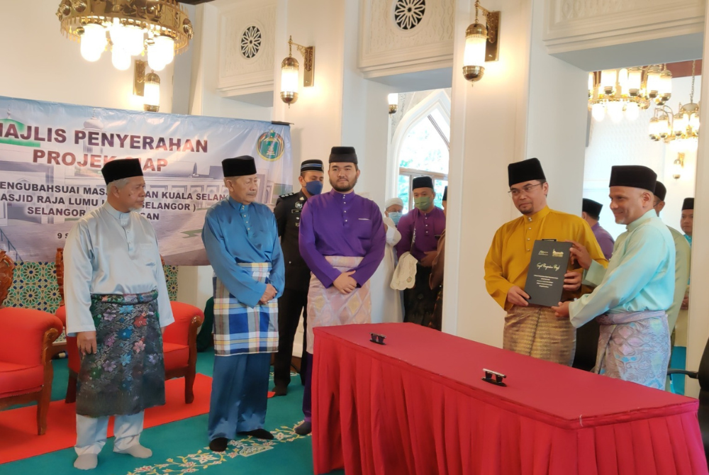 Pengarah Urusan Kumpulan Syarikat Rafulin, Datuk Mohamed Raffe Chekku (kanan) menyerahkan dokumen perjanjian kepada Mohd Shahzihan sambil diperhatikan Tengku Amir Shah (tiga dari kiri) pada Majlis Penyerahan Projek Siap Masjid Raja Lumu, Pekan Kuala Selangor pada Jumaat.