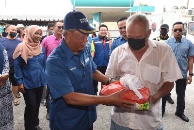 Muhyiddin beramah mesra bersama penduduk setempat yang hadir pada Jualan Prihatin PN di Bukit Pasir, Pagoh hari ini. - Foto Bernama