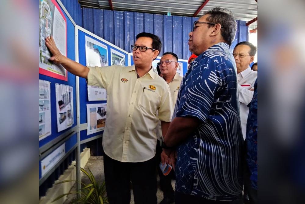 Abdul Latiff (kanan) mendengar taklimat Pembinaan Pejabat Negeri Pertahanan Awam Kelantan daripada Samsuri selepas merasmikan Majlis Pecah Tanah Projek Pembinaan Pejabat Negeri Pertahanan Awam Kelantan di Mukim Kota, Tunjong pada Ahad.