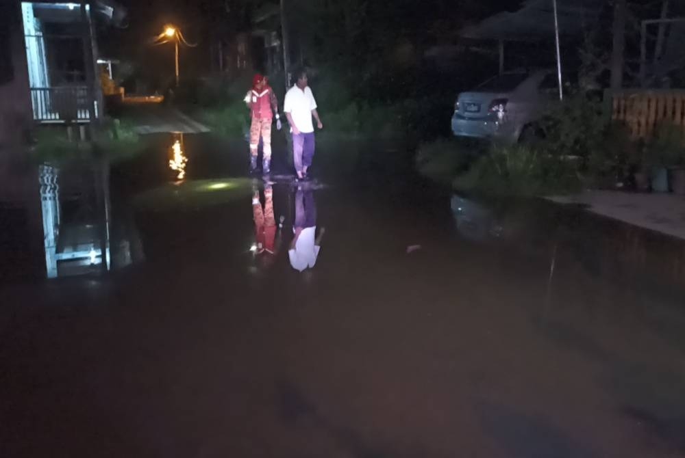 Anggota bomba dan penduduk meninjau keadaan sekitar Kampung Nelayan Benut yang dilanda air pasang pada malam Ahad.