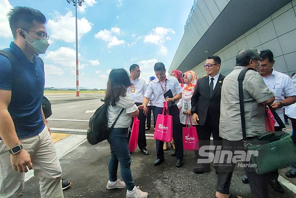 Muhammad Jailani (tengah) mengucapkan selamat datang kepada pelancong dari Pulau Pinang yang tiba du Lapangan Terbang Antarabangsa Melaka (LTAM) Batu Berendam di sini, pada Isnin.