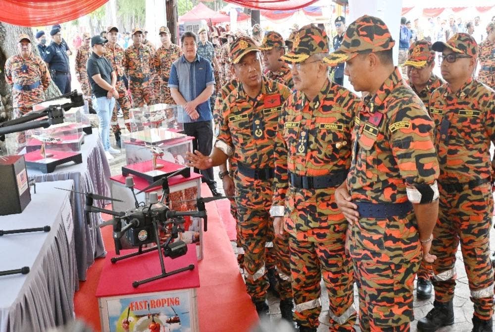 Nor Hisham (kanan) dan Nazili (kiri) memberi penerangan kepada Mohd Ali mengenai aset bomba di udara ketika Penutupan Kursus Pengurusan Bencana Peringkat Negeri di Pantai Puteri di sini pada Selasa.