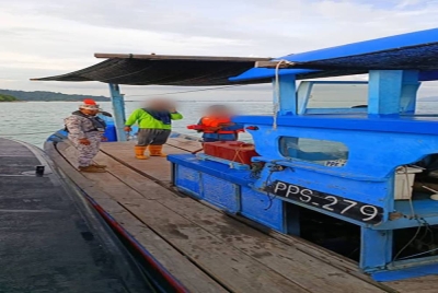 Anggota Maritim Malaysia memeriksa dua pekerja sangkar ikan.