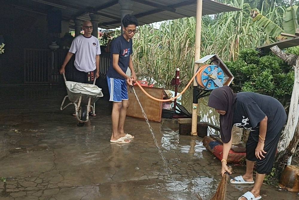 Penduduk membersihkan rumah selepas banjir mulai surut.