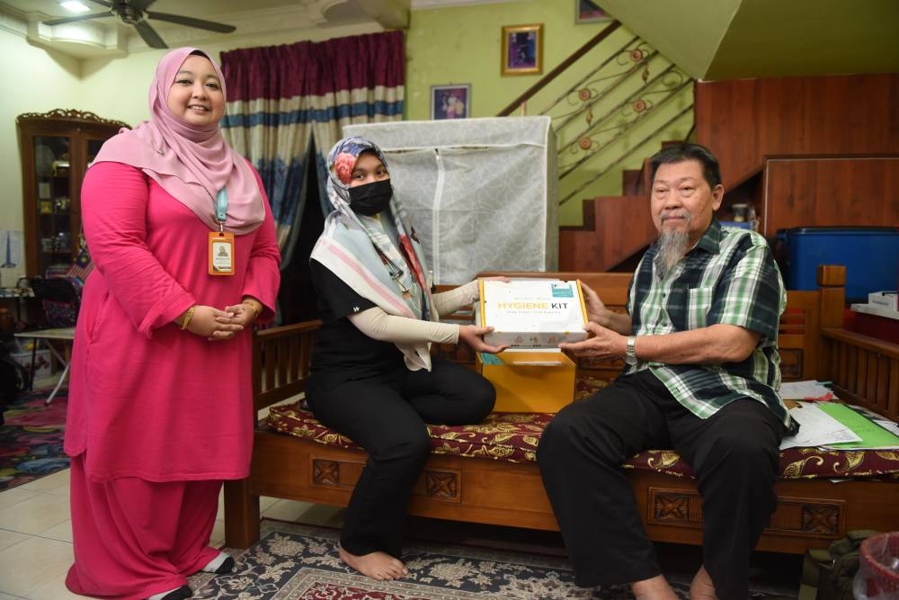 Dr Syakirah (tengah) turut menyampaikan kit kesihatan UPSC kepada bekas pesara polis itu.