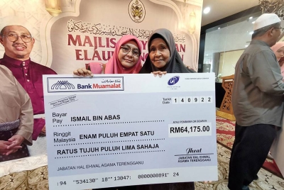 Ngah (kanan) bersama anaknya, Rosnidawati ketika menerima bayaran balik tunggakan elaun arwah suaminya di Wisma Darul Iman, pada Rabu.