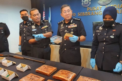 Cheng San (dua dari kanan) menunjukkan ketulan dadah mampat jenis ganja.