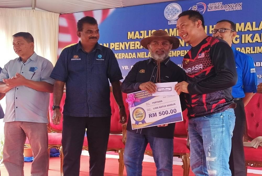 Syed Abu Hussin menyampaikan hadiah utama bagi kategori pertabdingan bot berhias yang diadakan sempena sambutan Hari Malaysia.