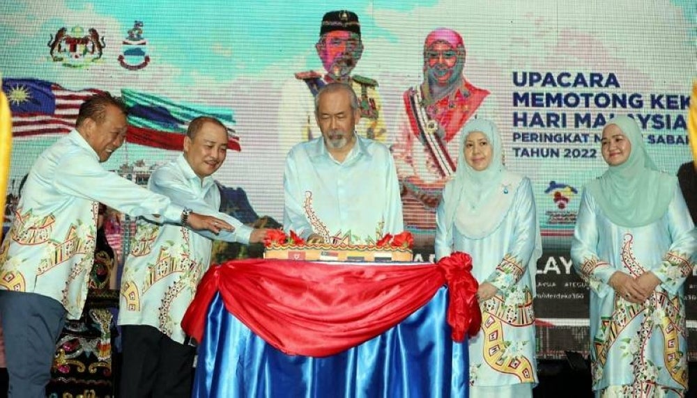 Juhar (tiga dari kiri) diiringi Hajiji (dua dari kiri) dan Bung Moktar (kiri) menyempurnakan upacara memotong kek Hari Malaysia pada Majlis Sambutan Hari Malaysia Peringkat Negeri Tahun 2022 di Padang Merdeka di Kota Kinabalu.