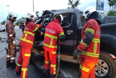 Anggota bomba menyelamatkan mangsa yang tersepit di bahagian penumpang hadapan. - Foto JBPM