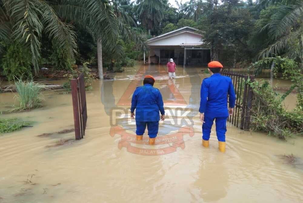 Anggota APM meredah banjir bagi membantu memindahkan mangsa ke PPS yang dibuka di Dewan Semanggol, di sini pada Ahad. - FOTO APM Perak
