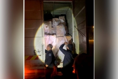 Anggota polis memeriksa belakang sebuah lori yang membawa rokok seludup selepas menahannya berhampiran lampu isyarat simpang empat Jalan Sungai Rengit-Kota Tinggi, Kota Tinggi pada Sabtu.