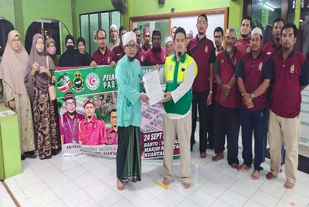 Rosli (kiri) menerima borang pendaftaran Sukarelawan Banjir Pas Kuantan diserahkan Saharudin di Masjid Al Fatah, Batu 3 di sini pada malam Sabtu.