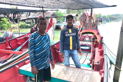 Nik Ruzullaili (kanan) dan Azman (kiri) yang tidak dapat menurunkan perahu kolek mereka ke laut kerana sungai cetek.