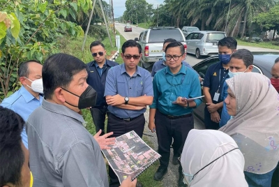 Loy Sian (kiri) menerangkan sesuatu semasa melawat ladang ternakan babi di Tanjung Sepat, Kuala Langat.