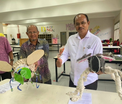 Che Alias (kiri) dan Razali menunjukkan antara karya daripada barang terbuang dihasilkan peserta. 