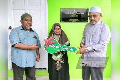 Ahmad (kanan) menyerahkan replika kunci rumah kepada Rahimah pada Majlis Penyerahan Rumah Dhuafa di Kampung Kutan pada Khamis.