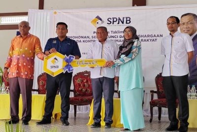 Mohd Nizar (tengah) menyerahkan replika kunci kepada salah seorang pemilik RMR ketika program Taklimat Permohonan, Serah Kunci dan Penghargaan kepada kontraktor RMR di Arena Square Parit pada Khamis.