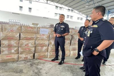 Mohd Shuhaily (kiri) menunjukkan 1.9 juta batang rokok seludup yang dirampas.