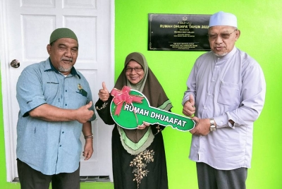 Ahmad (kanan) menyampaikan replika kunci kepada Rahimah, 64, Majlis Penyerahan Rumah Dhuafa pada Khamis.