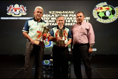 Emran (tengah) bersama Hashim (kiri) bersama piala yang bakal menjadi rebutan pasukan dalam Kejohanan Bola Sepak Piala Datuk Mokhtar Dahari.