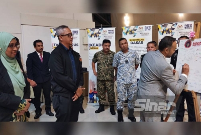 Nurhayati (kiri) dan Mohd Zawawi (tiga kiri) melihat Pengarah Bahagian Perisikan dan Pengurusan Krisis Negara, Tajul Ariffin Muhammad menandatangani papan kanvas sebagai simbolik menyokong usaha menggemakan gelombang melawan rasuah di negara ini.