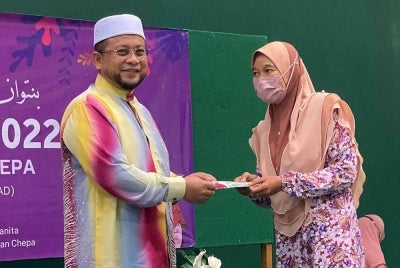 Ahmad Marzuk (kiri) menyampaikan sumbangan kepada salah seorang penerima semasa merasmikan Hari Sayyidatina Khadijah Parlimen Pengkalan Chepa di Putik pada Ahad.