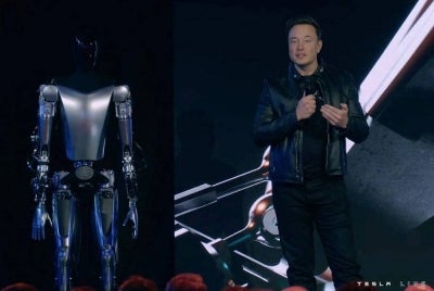 Musk (kanan) memperkenalkan robot Optimus (kiri) pada satu majlis di Silicon Valley baru-baru ini. - Foto AFP