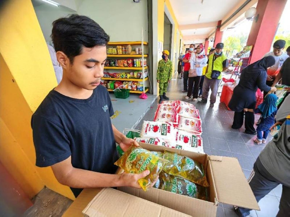 Pekerja menyusun minyak masak paket untuk dijual kepada pelanggan yang sudah beratur. 