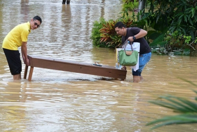 Penduduk Kampung Paya Kenangan mengalihkan barangan apabila rumah mereka dinaiki air berikutan banjir kilat ketika tinjauan pada Rabu. - Foto Bernama