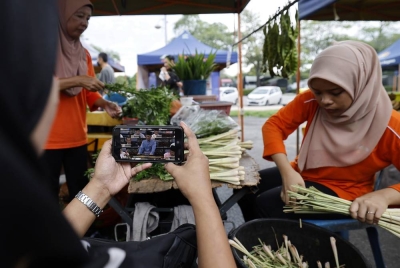 Peniaga di Pasar Malam Presint 2 Putrajaya mengikuti siaran langsung pembentangan Bajet 2023. - Foto Bernama
