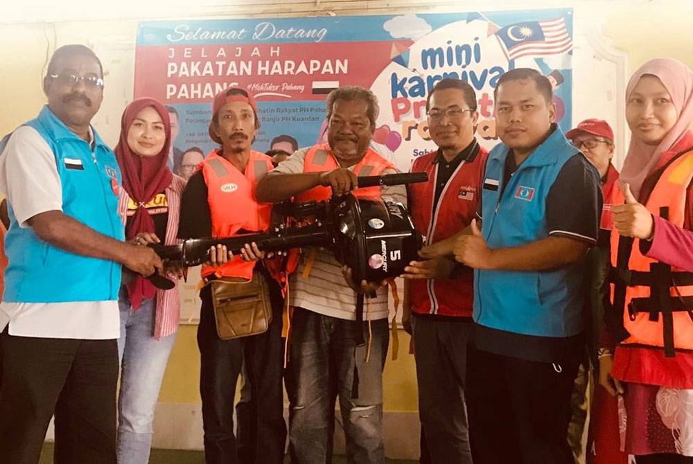 Young Syefura (dua, kiri) menyerahkan enjin bot kepada sukarelawan banjir PH selepas majlis perasmian Jelajah PH Pahang bertemakan MohTukar Pahang yang diadakan di Kampung Razali di sini pada Sabtu.