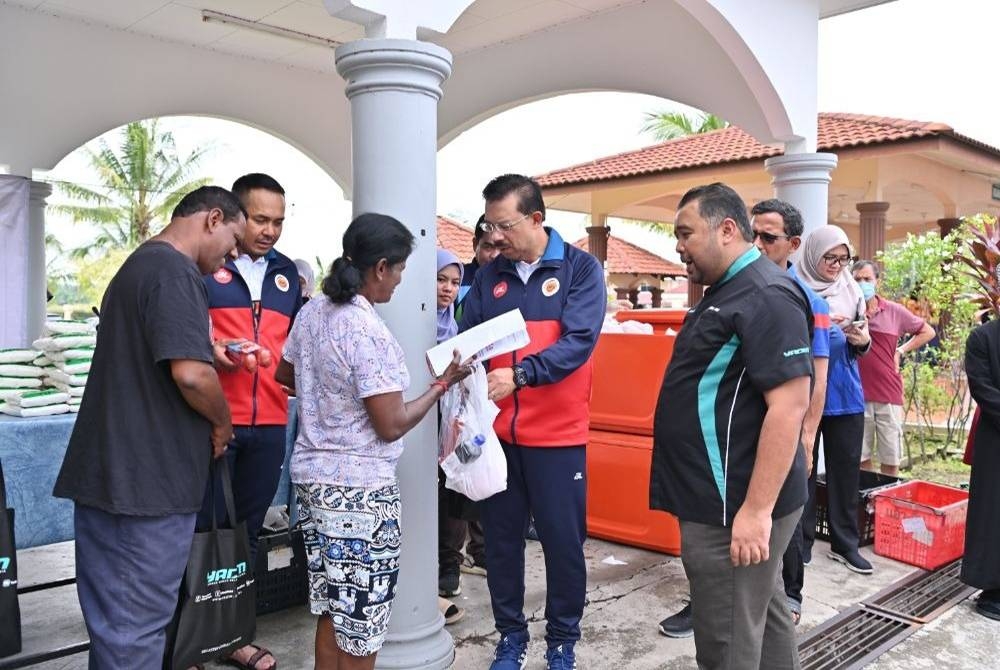 Mohd Zuki (dua dari kiri) ketika menyampaikan sumbangan berkenaan kepada masyarakat bukan Islam.