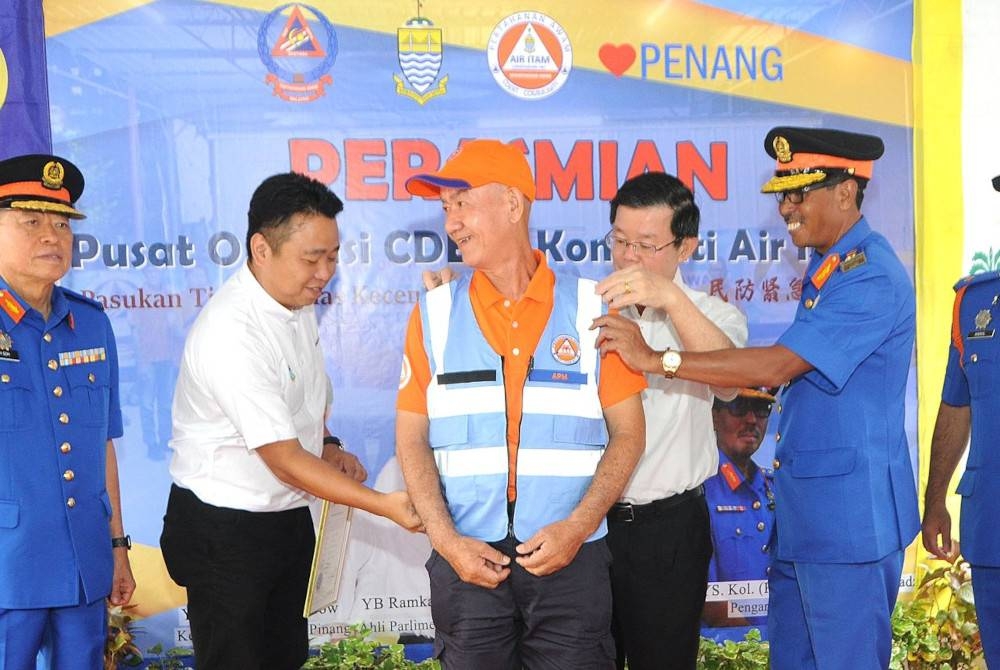Kon Yeow (dua dari kanan) memakaikan jaket CDERT ketika merasmikan Pasukan CDERT Air Itam pada Ahad.