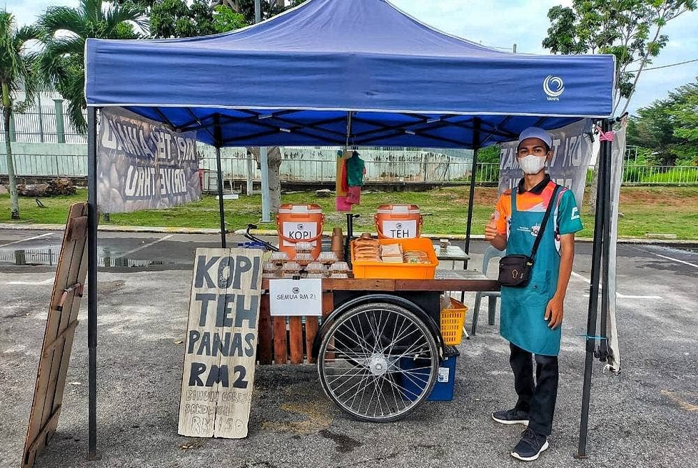 Ahmad Usamah (kiri) menjual kopi dan teh panas di Klebang, Melaka.