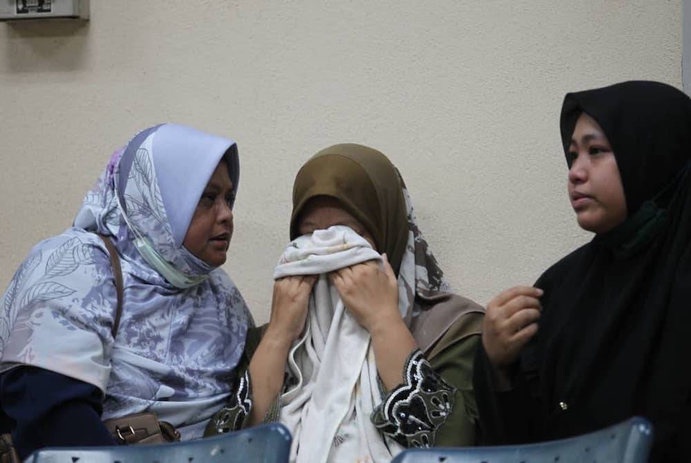 Nor Asikin (tengah) tidak dapat menahan sebak ketika menunggu proses bedah siasat dijalankan di Jabatan Forensik, HRPB pada Selasa.