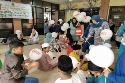 Wan Azliana (berdiri kanan) bersama petugas mengagihkan belon Rasuah Busters kepada kanak-kanak bagi memupuk antirasuah dalam diri golongan sasar tersebut.