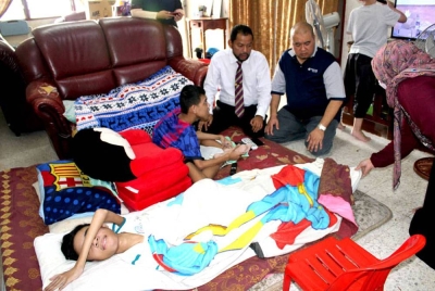 Syaiful Rizal (kiri) dan Mohamad Ghazali (kanan) ketika menyerahkan sumbangan kepada keluarga tiga beradik OKU itu kediaman mereka di Nilai, Negeri Sembilan.