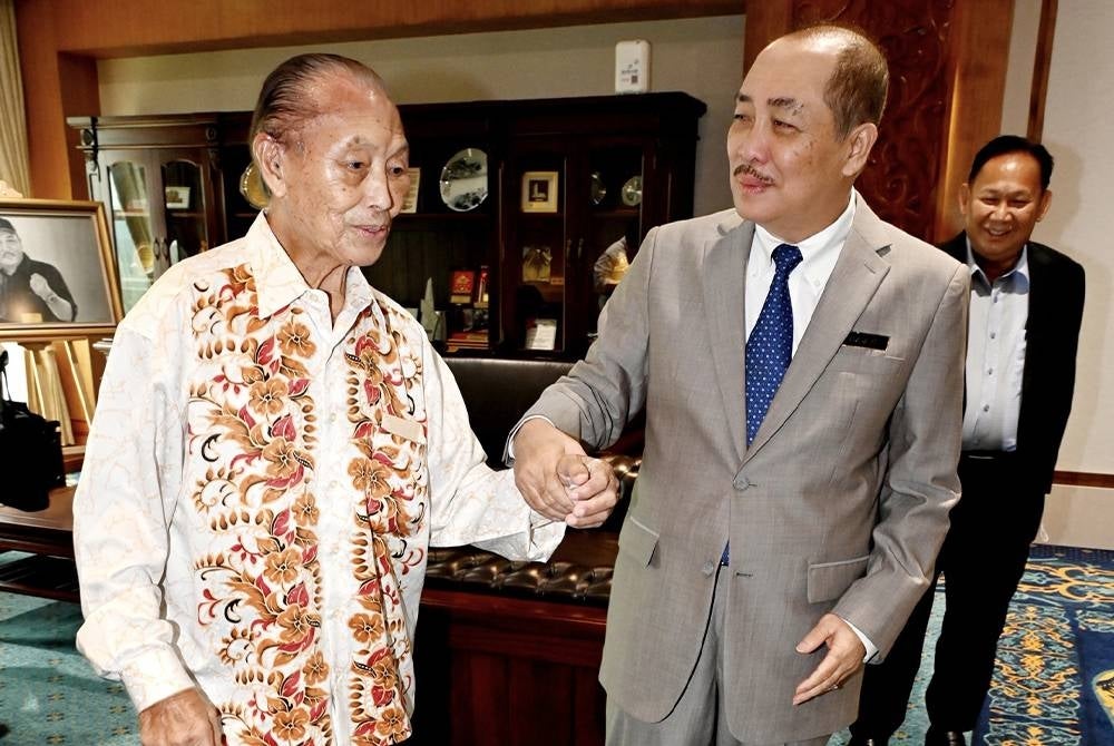 Hajiji (kanan) memimpin tangan Buatin Blandong semasa menerima kunjungan warga emas luar biasa itu di pejabatnya di Menara Kinabalu, Kota Kinabalu pada Rabu. - Foto Bernama