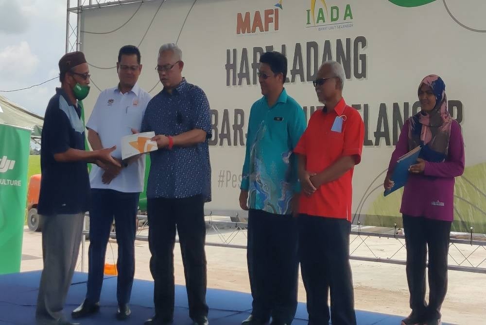 Noh (tiga dari kiri) menyampaikan sijil penghargaan kepada ketua blok sawah padi ketika Majlis Perasmian Hari Ladang di Pusat Belian Padi Sungai Burong pada Khamis.