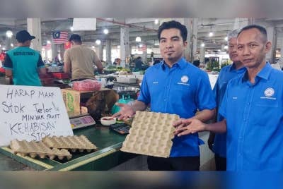 Mohammad Yusrizal (kiri) menunjukkan sebahagian kedai runcit di Pasar Besar Alor Setar yang sudah kehabisan bekalan telur dan minyak peket pada pagi Khamis.