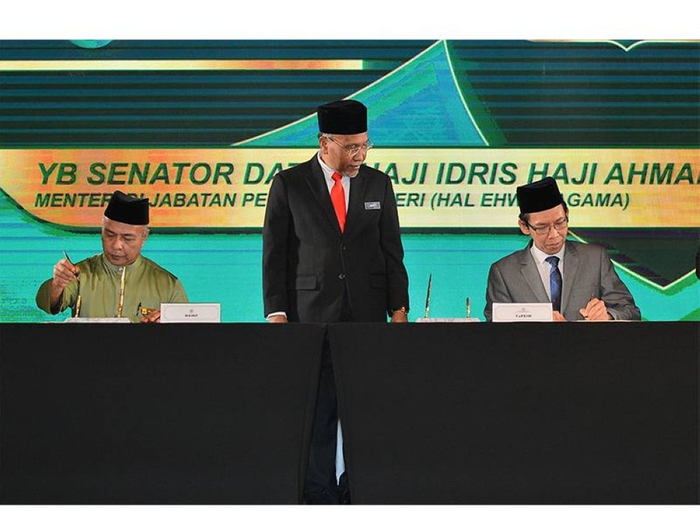 Menteri di Jabatan Perdana Menteri (Hal Ehwal Agama), Datuk Idris Ahmad menyaksikan Awang (kanan) dan Pemangku Ketua Pegawai Eksekutif MAIWP, Mohd Nizam Yahya menandatangani memorandum persefahaman (MoU) antara YaPEIM) dan MAIWP pada Majlis Pelancaran Program Pembangunan Ekonomi dan Keusahawanan Asnaf di Hotel Sunway Putra pada Rabu.