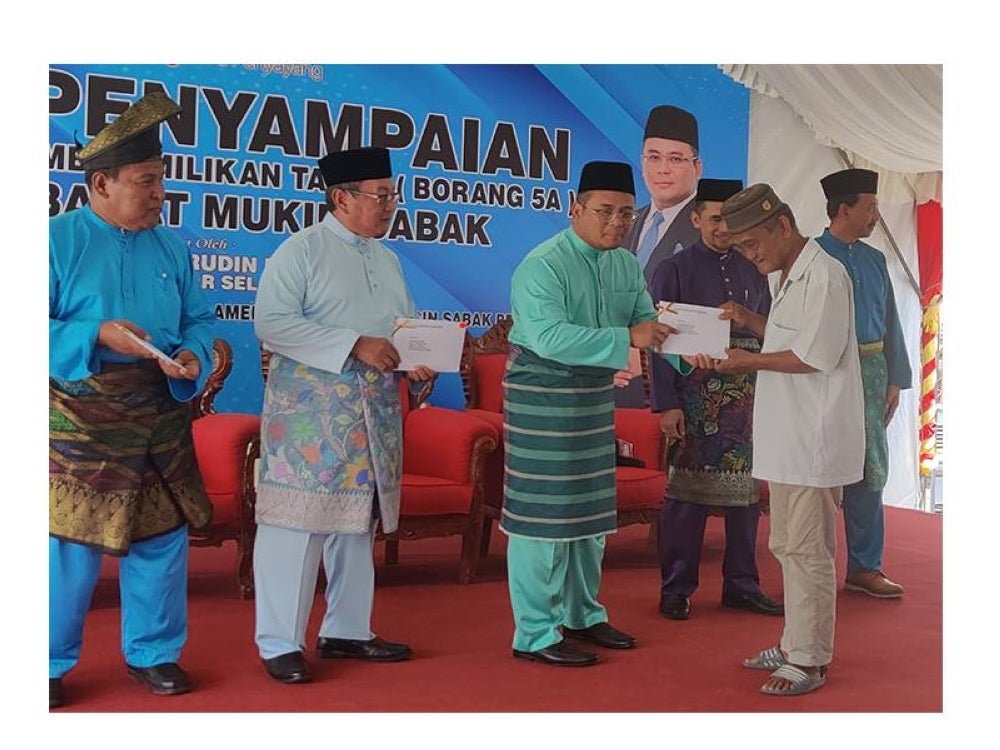 Amirudin (tiga dari kiri) menyampaikan surat hak milik kepada salah seorang penerima pada Majlis Penyampaian Surat Kelulusan Hak Milik Tanah Borang 5A Parit 8 1/2 Barat Mukim Sabak di pekarangan Masjid Jamek Sultan Hishamudin di sini pada Jumaat.