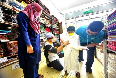 Noor Herra melihat Zulkifli memakaikan kain ihram untuk anaknya, Muhammad Danish Riza Hadi, 6.