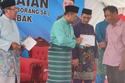 Amirudin (dua dari kiri) menyampaikan surat hak milik kepada salah seorang penerima pada Majlis Penyampaian Surat Kelulusan Hak Milik Tanah Borang 5A Parit 8 1/2 Barat Mukim Sabak di pekarangan Masjid Jamek Sultan Hishamudin di sini pada Jumaat.