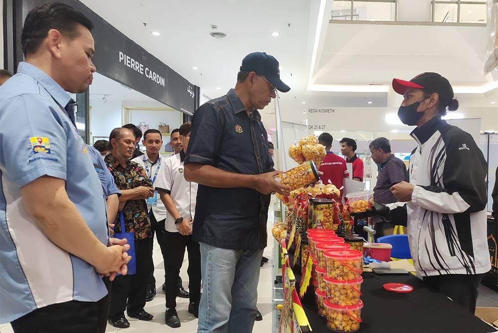 Rosol (tengah) melibat produk keluaran pengusaha tempatan selepas merasmikan Kempen Beli Barangan Malaysia peringkat negeri Terengganu, pada Sabtu.
