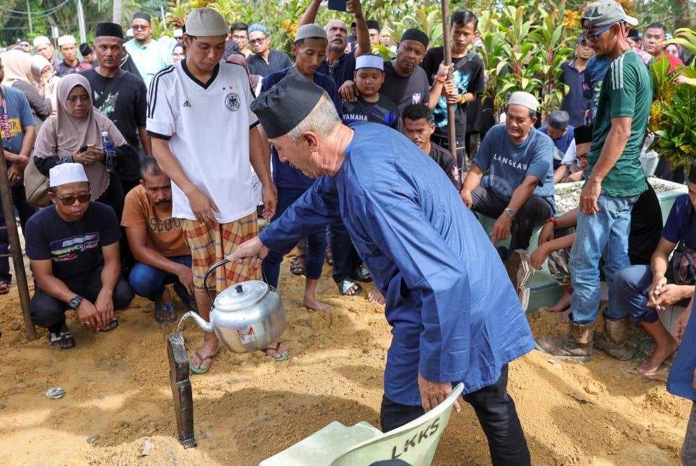 Kamalul Arifin (tiga dari kiri) Redzuan (dua dari kiri) menyiram pusara anaknya, Nurul Nazihah yang selamat dikebumikan di Tanah Perkuburan Islam Kampung Temenin Lama, hari ini. - Foto Bernama
